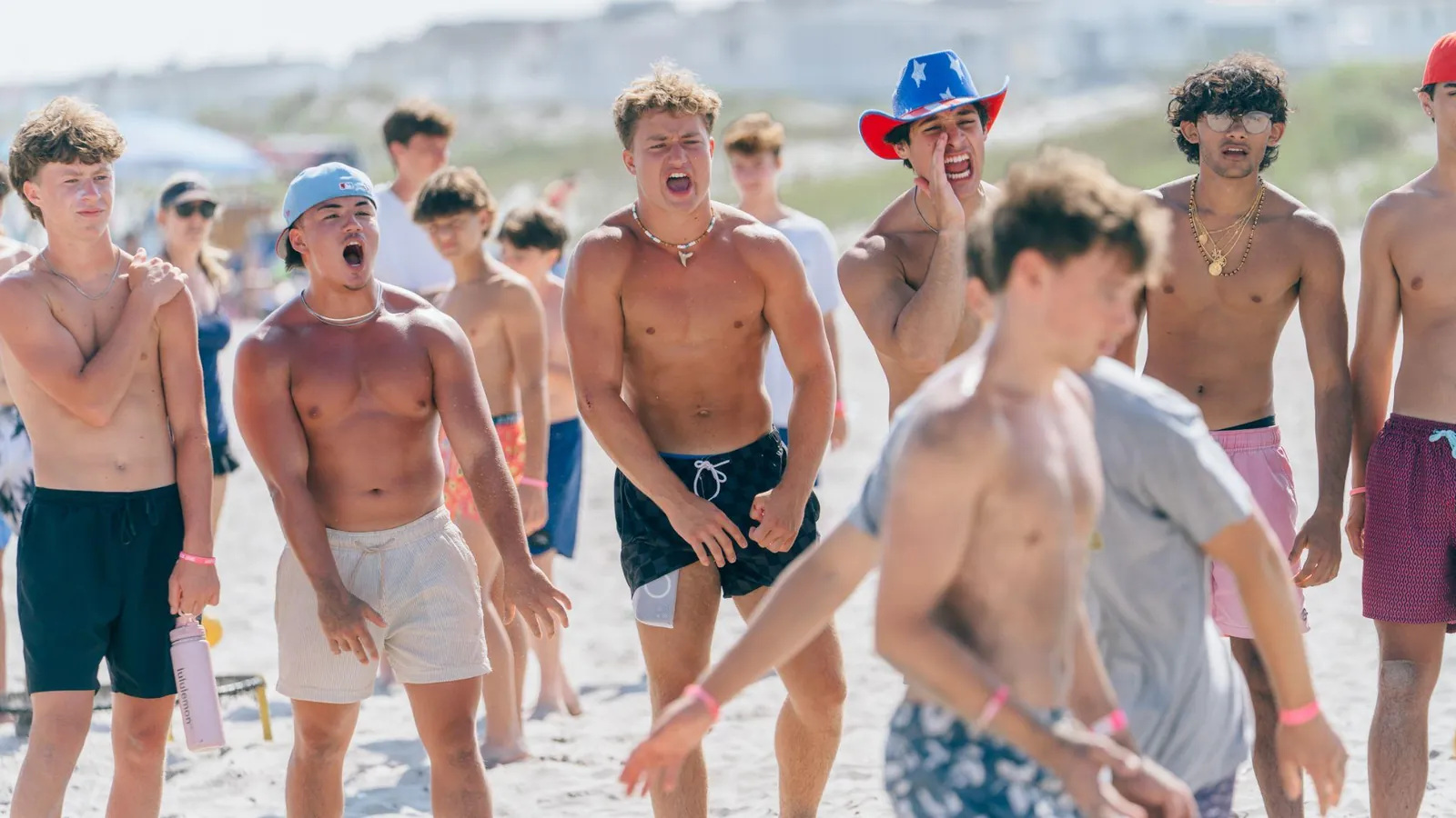 A pack of players roaring on the sand mid-rally