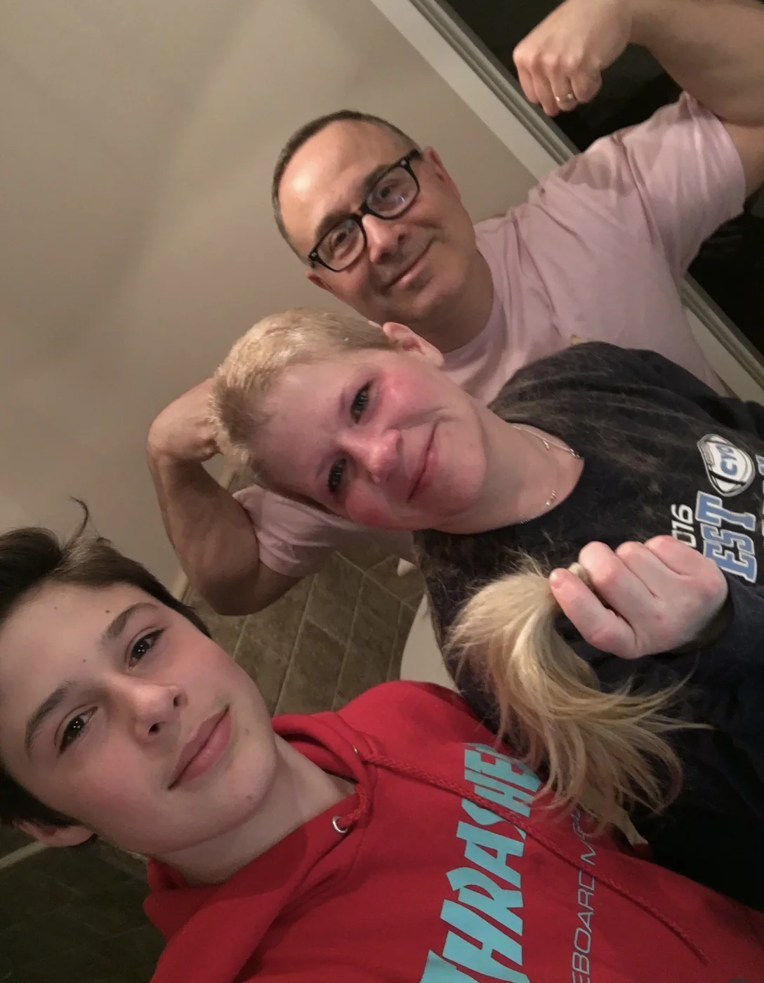Zeke at age twelve with his mom, her head newly shaved, and his dad flexing behind them, all smiling for the camera